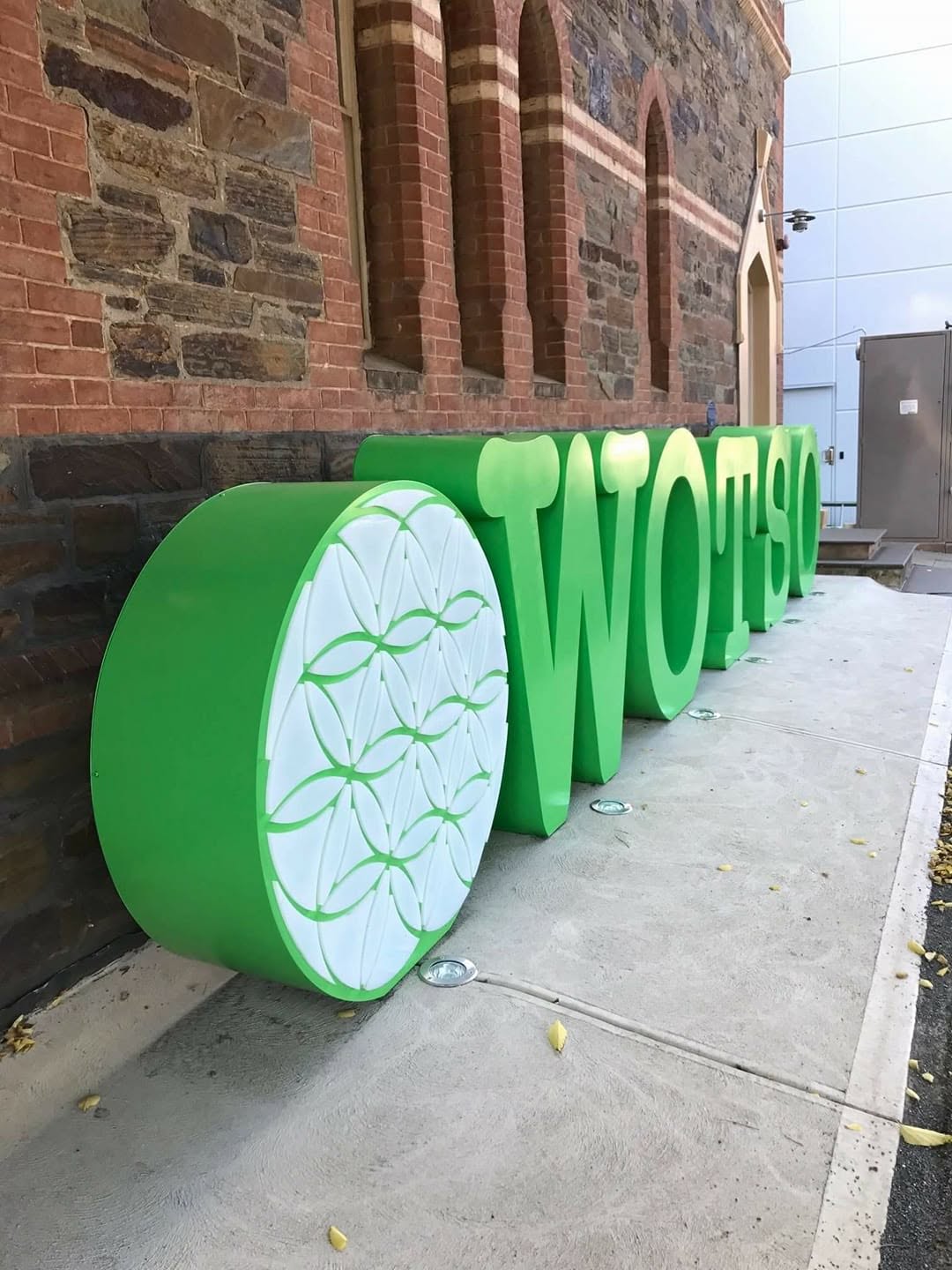 Fabricated 3D letters and logo disc against a brick facade